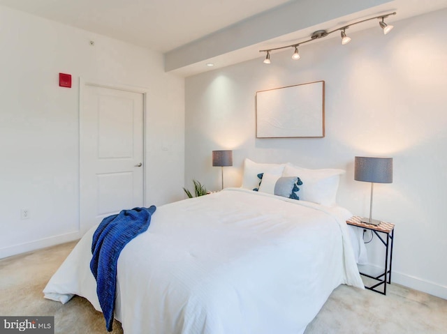 carpeted bedroom featuring track lighting and baseboards