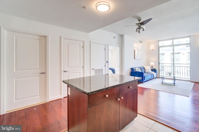 kitchen featuring dark stone counters, light wood-style floors, a center island, and floor to ceiling windows