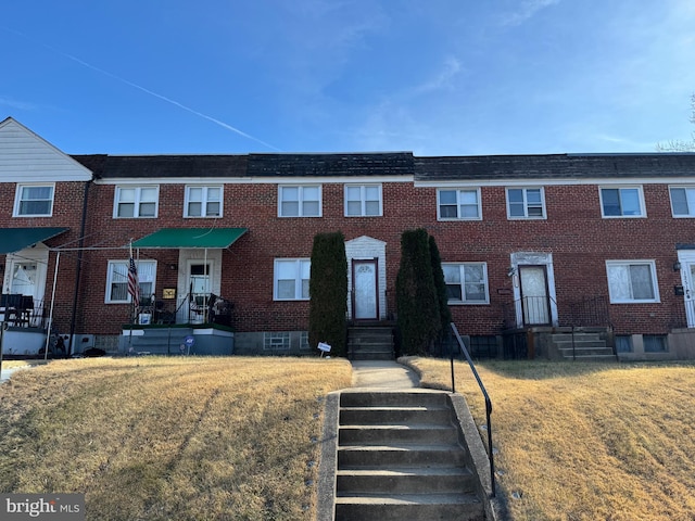 multi unit property featuring a front lawn and brick siding