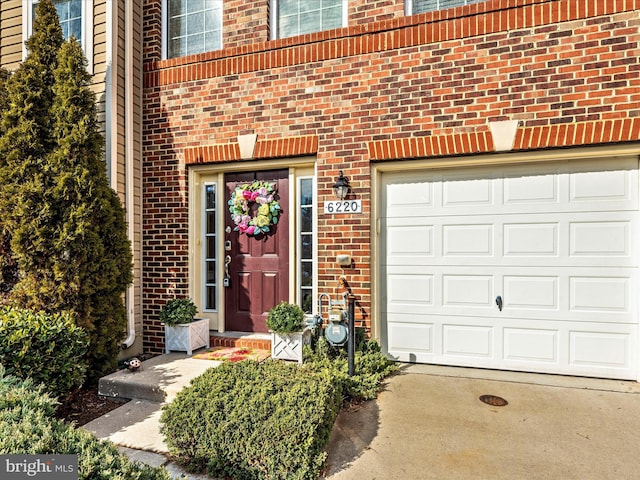 doorway to property with an attached garage and brick siding