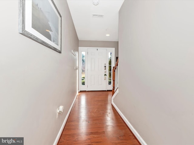 entryway with stairs, wood finished floors, visible vents, and baseboards