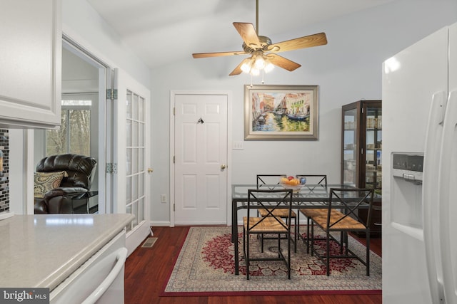 dining area with visible vents, dark wood-type flooring, a ceiling fan, baseboards, and vaulted ceiling