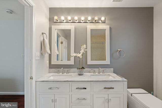 bathroom featuring a sink, visible vents, toilet, and double vanity