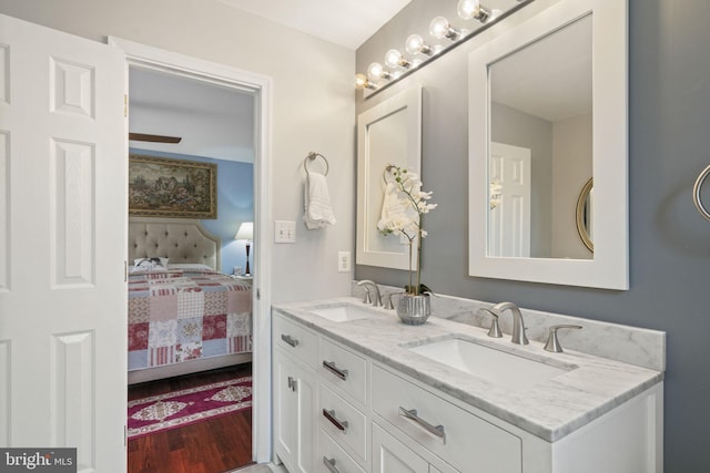 bathroom with a sink, double vanity, wood finished floors, and ensuite bathroom