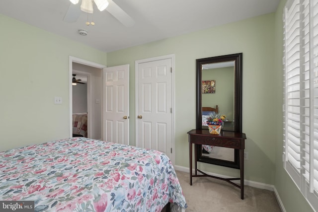 bedroom featuring baseboards, light colored carpet, and a ceiling fan