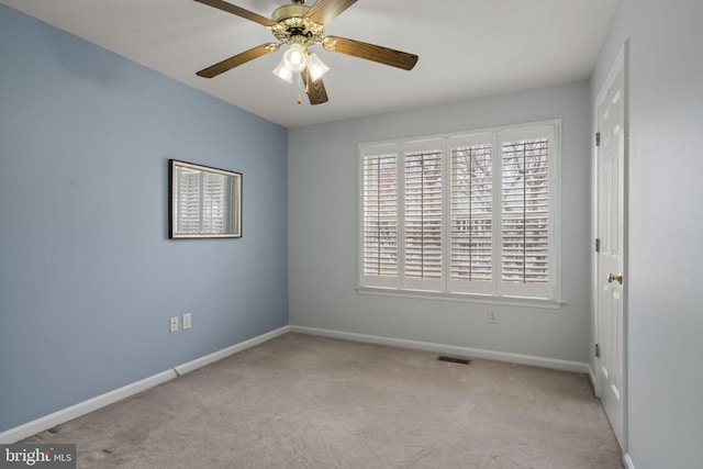 spare room with carpet flooring, baseboards, visible vents, and a ceiling fan