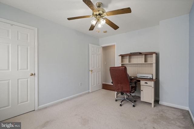 office space featuring baseboards, light carpet, and a ceiling fan