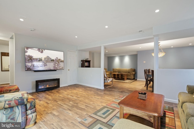 living area featuring recessed lighting, baseboards, a glass covered fireplace, and light wood-style flooring