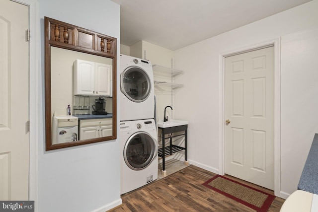 laundry area with baseboards, laundry area, stacked washer and clothes dryer, dark wood-style floors, and a sink