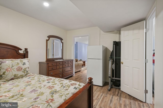 bedroom featuring light wood-style floors and freestanding refrigerator