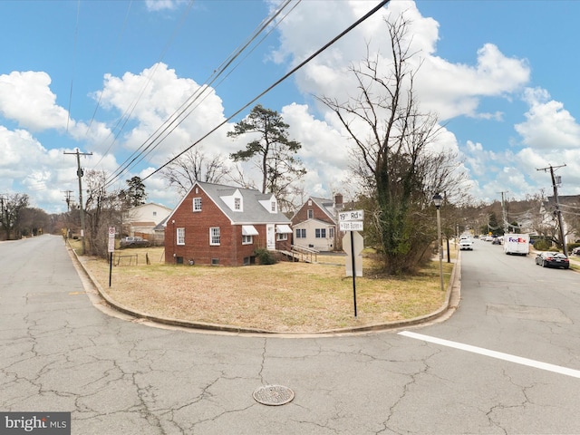 view of road featuring traffic signs, a residential view, and curbs