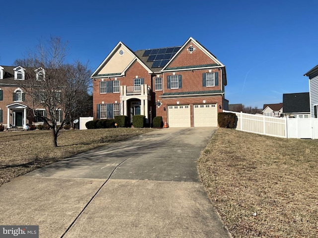 view of front of home featuring brick siding, roof mounted solar panels, fence, a garage, and driveway