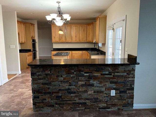 kitchen featuring dark countertops, light brown cabinets, a sink, and double wall oven