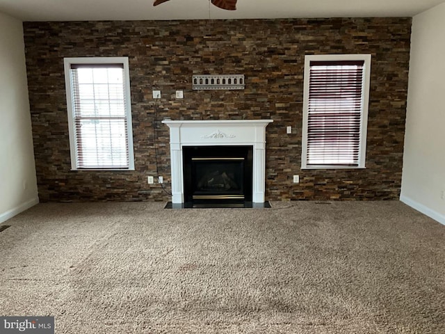 unfurnished living room with a fireplace with flush hearth, carpet, ceiling fan, and baseboards