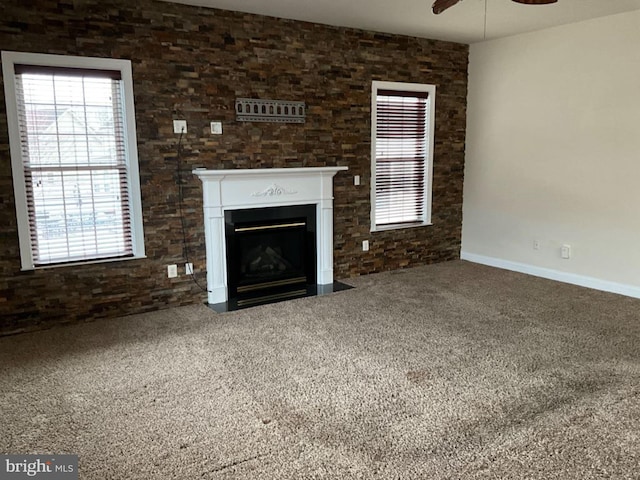 unfurnished living room featuring carpet, a fireplace with flush hearth, and a healthy amount of sunlight