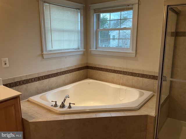 bathroom featuring a stall shower, a garden tub, and vanity