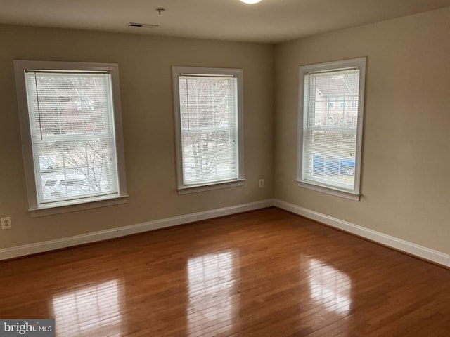 unfurnished room with baseboards and hardwood / wood-style floors