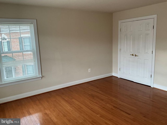 unfurnished bedroom featuring a closet, hardwood / wood-style floors, and baseboards