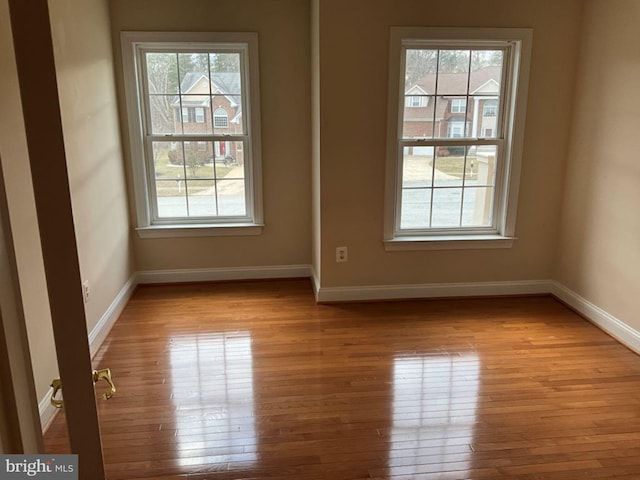 spare room with plenty of natural light, baseboards, and hardwood / wood-style flooring