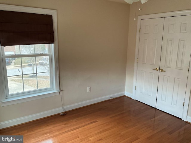 unfurnished bedroom featuring a closet, baseboards, and wood finished floors