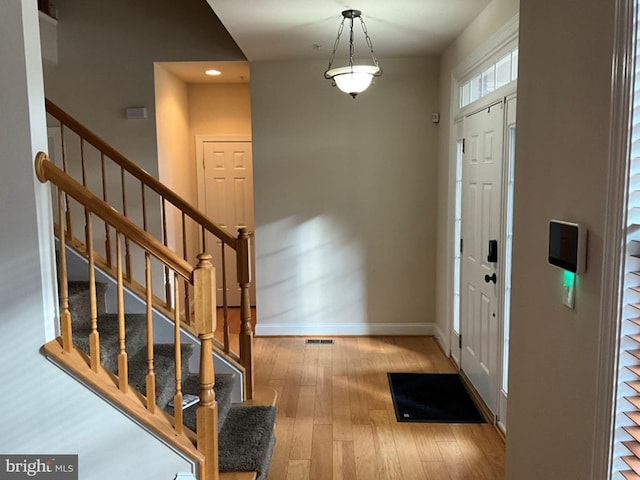 entrance foyer with stairway, hardwood / wood-style floors, and baseboards