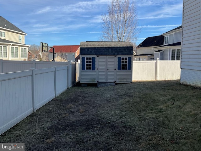 exterior space with a shed, an outdoor structure, a fenced backyard, and a residential view