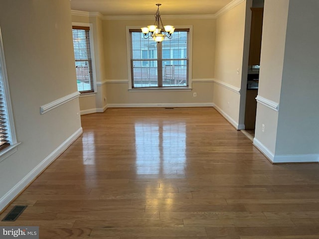 unfurnished dining area with a healthy amount of sunlight, an inviting chandelier, visible vents, and crown molding