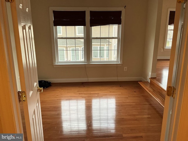 spare room featuring baseboards and wood finished floors