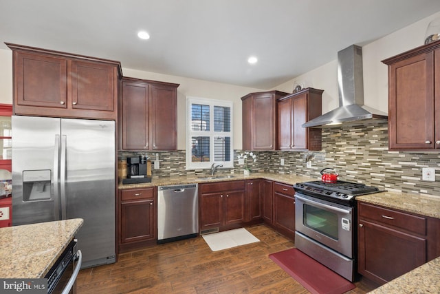 kitchen featuring dark wood-type flooring, a sink, backsplash, stainless steel appliances, and wall chimney range hood