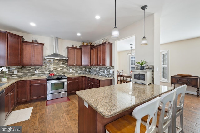 kitchen with stainless steel gas stove, tasteful backsplash, dark wood finished floors, wall chimney exhaust hood, and dishwashing machine