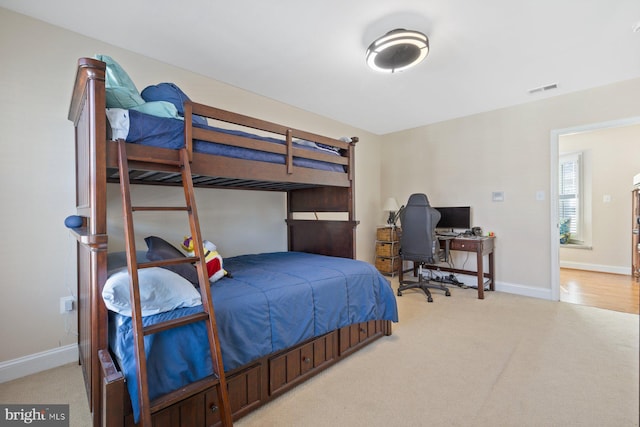 bedroom featuring visible vents, light carpet, and baseboards