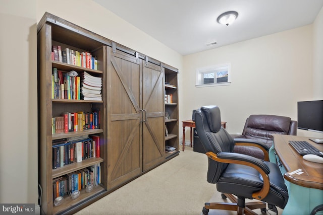 home office featuring a barn door, carpet floors, and visible vents