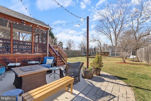 view of patio featuring a deck, a trampoline, and a fenced backyard