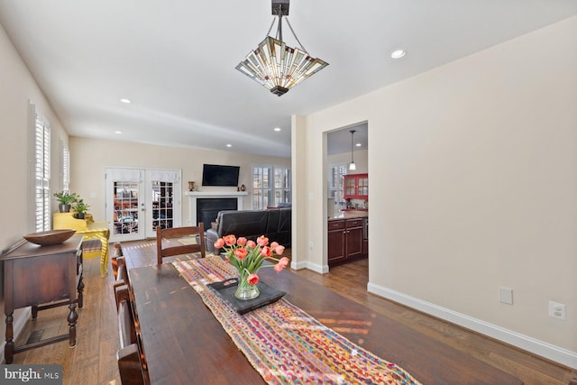 dining area featuring dark wood-style floors, a fireplace, baseboards, and a wealth of natural light