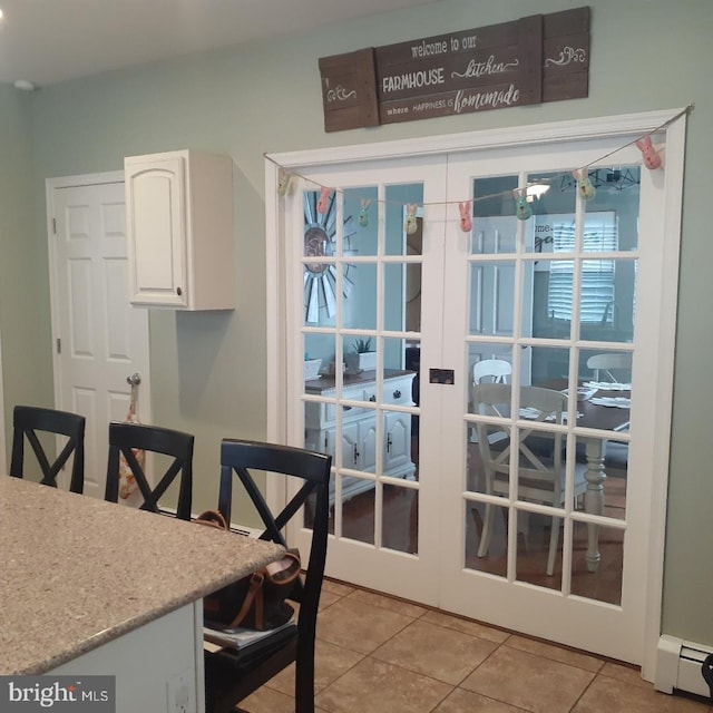 dining space featuring a baseboard radiator, light tile patterned flooring, and french doors