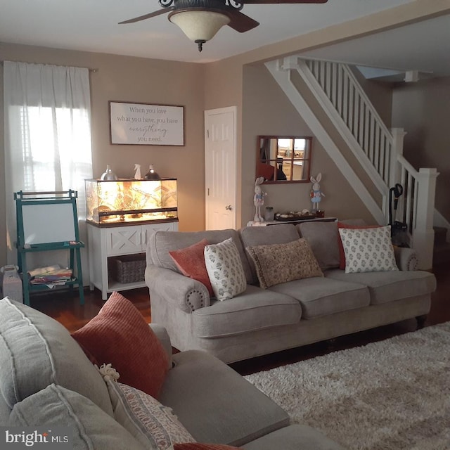 living area featuring stairway, dark wood-type flooring, and a ceiling fan