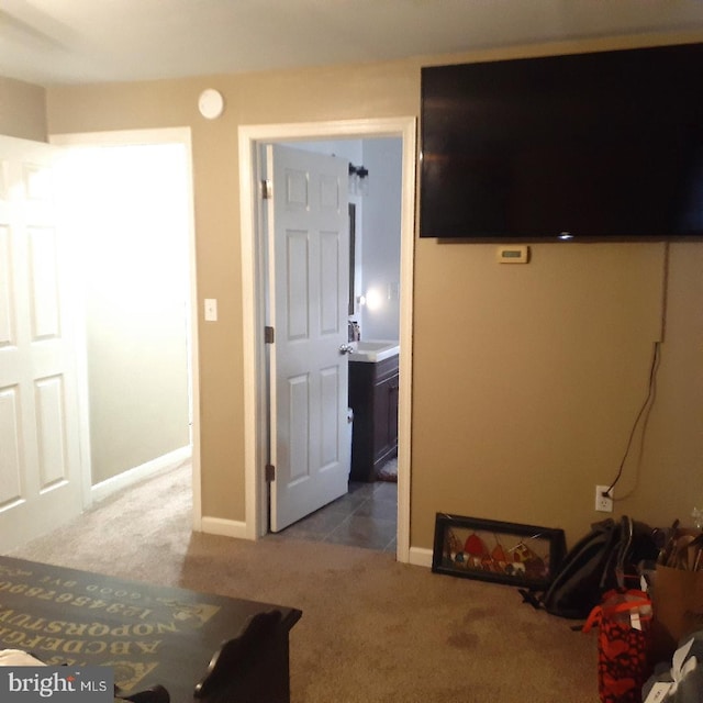 carpeted bedroom featuring a sink and baseboards