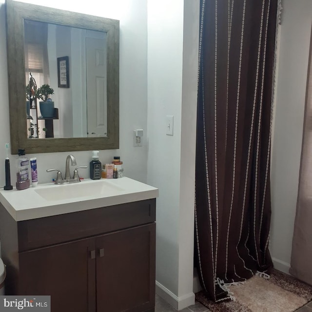 bathroom with a shower with shower curtain, vanity, and baseboards