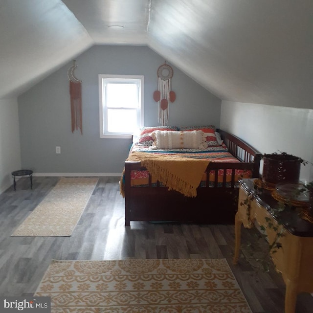 bedroom featuring lofted ceiling, wood finished floors, and baseboards