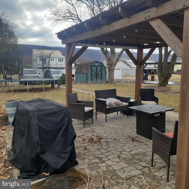 view of patio with a storage shed, a trampoline, an outdoor structure, and a grill