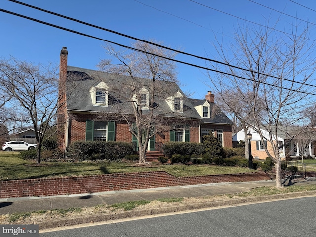 cape cod-style house featuring a front lawn, brick siding, and a chimney