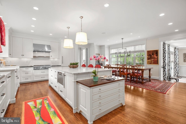 809 Cornell St, Fredericksburg, VA 22401 - kitchen with decorative backsplash, stainless steel gas cooktop, a kitchen island, wall chimney exhaust hood, and white cabinets