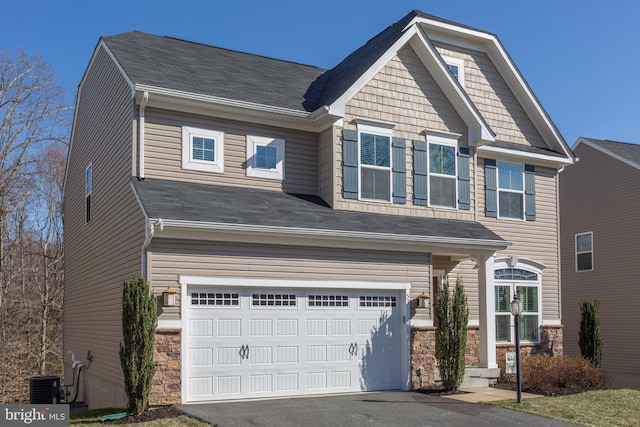 craftsman house with cooling unit, stone siding, driveway, and an attached garage