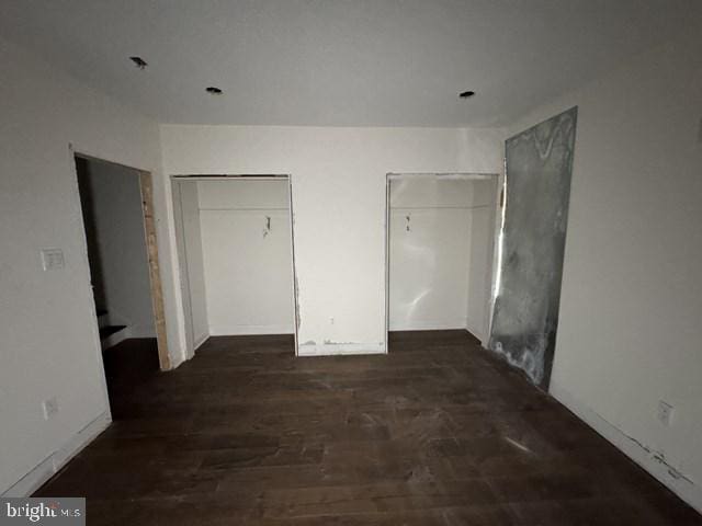 unfurnished bedroom featuring wood finished floors and multiple closets