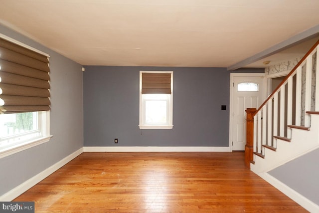 foyer entrance with stairway, baseboards, and wood finished floors