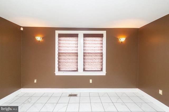 spare room with marble finish floor, visible vents, and baseboards