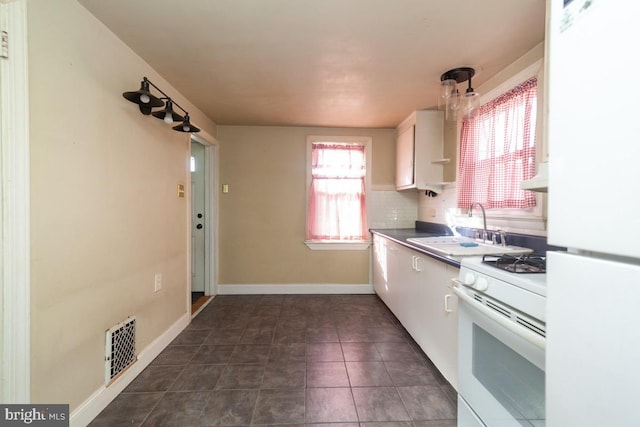 kitchen featuring visible vents, backsplash, white cabinets, a sink, and white appliances