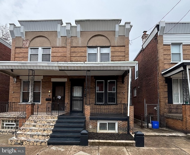 townhome / multi-family property with covered porch and brick siding