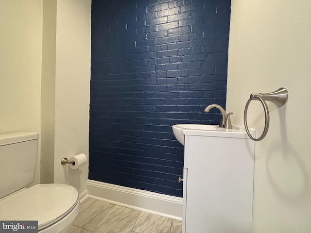 bathroom with toilet, baseboards, and a sink