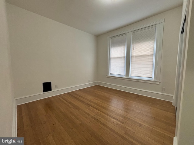 spare room featuring dark wood-style floors and baseboards